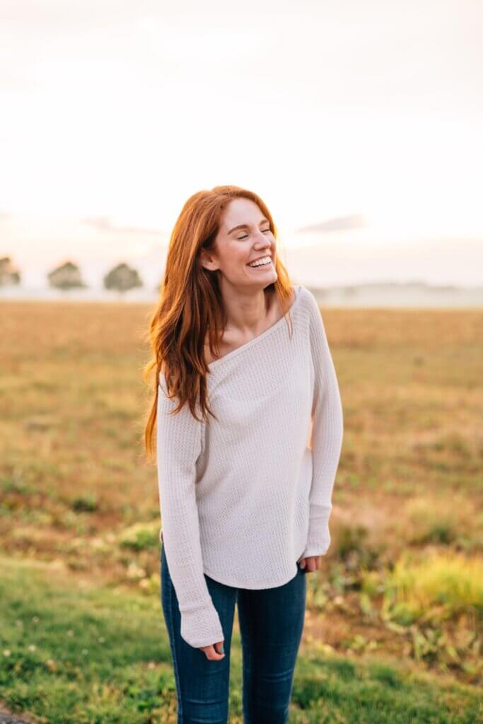 woman smiling in field with red hair
