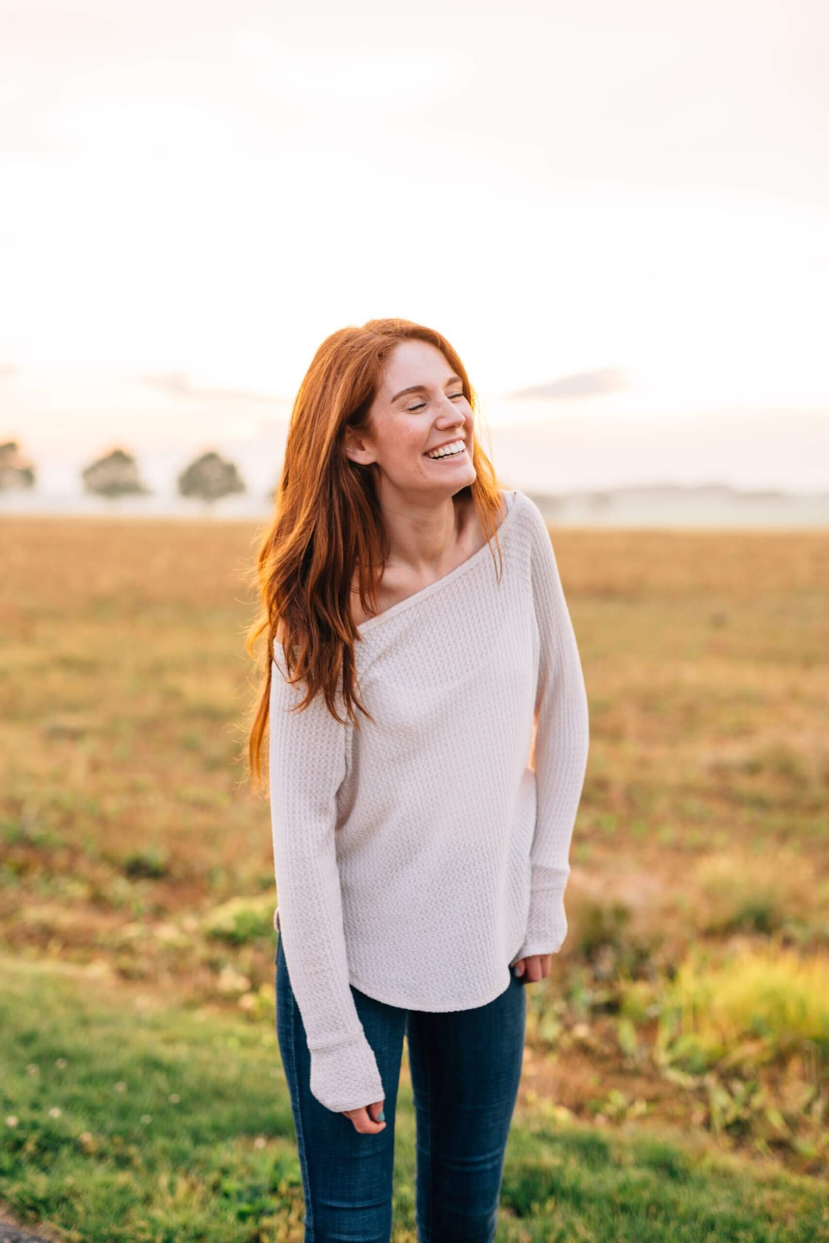 woman smiling in field with red hair