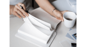 woman hands flipping through notebook holding a coffee mug