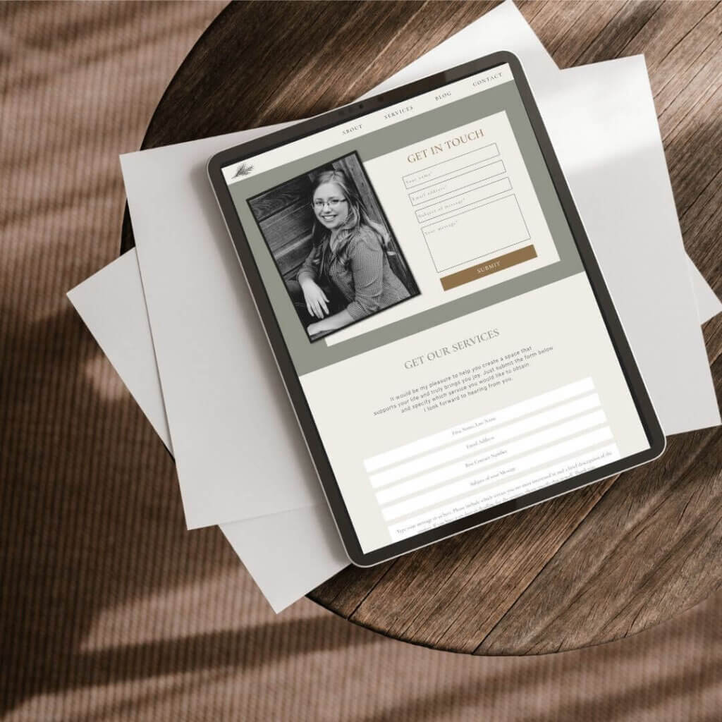 Picture of ipad on showing the contact page of the Spruce Design & Co website.  Ipad is on top of white papers on a round brown table